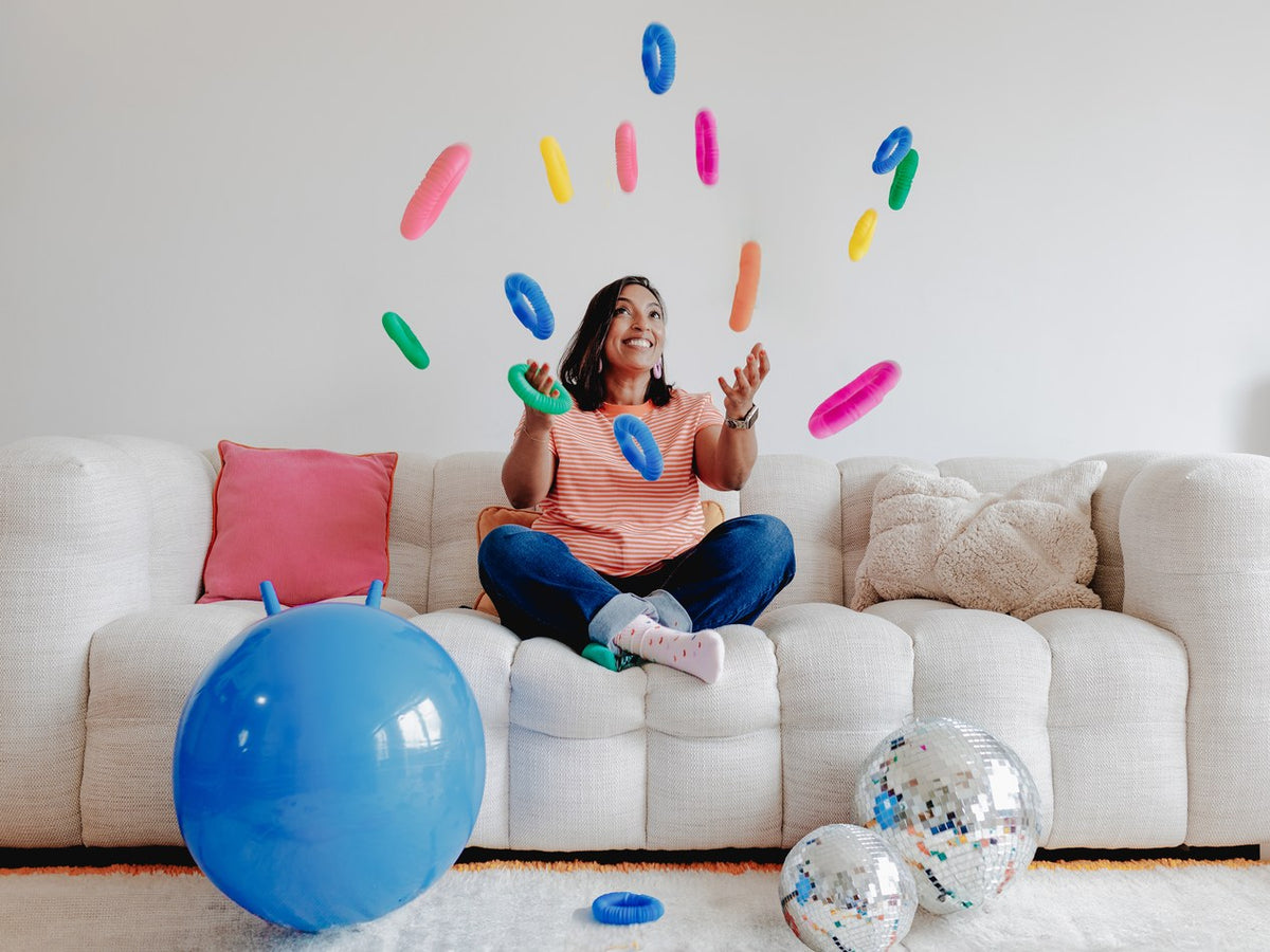 Siham Yara jonglant avec des bigoudis colorés sur un canapé, projet L'Extratypik
