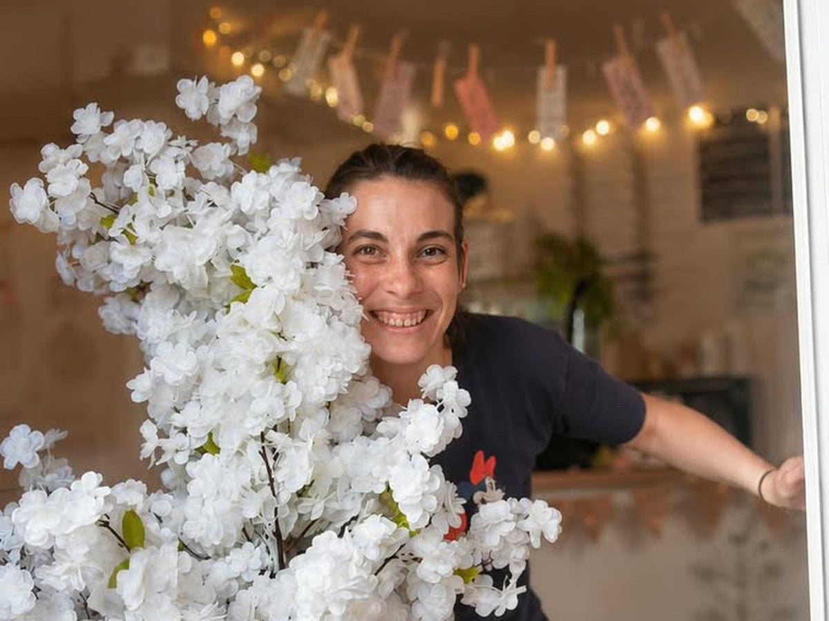 Laura Najar dans le salon de thé Mama Café, entourée de fleurs blanches